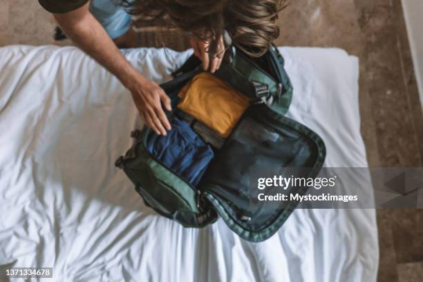 top view of male traveler packing for a trip, puts clothes in a duffel bag - ingepakt stockfoto's en -beelden