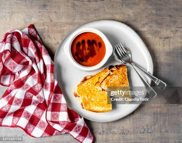 bowl of tomato soup with grilled cheese sandwich on a plate on wooden background - soup and sandwich stock pictures, royalty-free photos & images