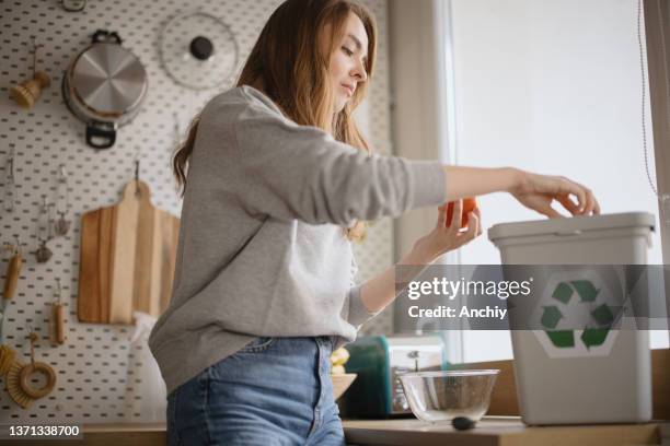 young woman peeling orange into  recycling bin, compost bin - garbage dump bildbanksfoton och bilder