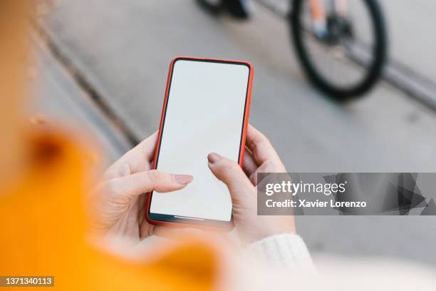 young woman using mobile phone with blank screen in city street - frau mit handy screen stock-fotos und bilder