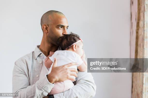 stay-at-home-vater schaut aus dem fenster, während er baby trägt - baby depression stock-fotos und bilder