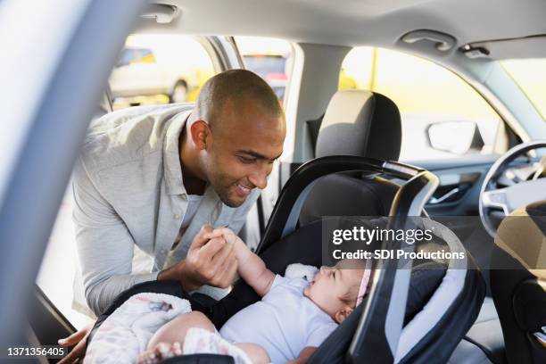 父は赤ちゃんに微笑むために車の後部に身を乗り出す - baby　smile ストックフォトと画像