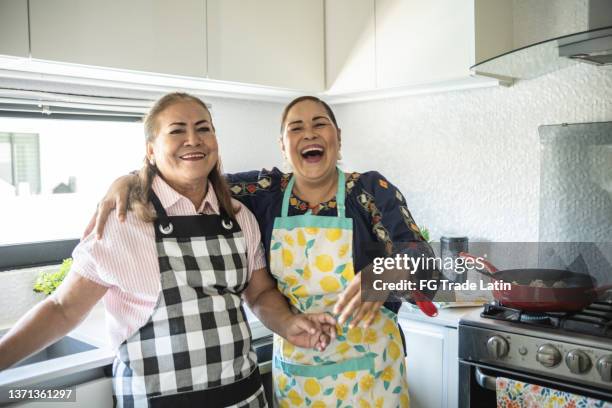 portrait of female latin friends laughing at home - woman laugh cook stock pictures, royalty-free photos & images