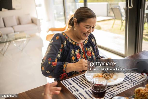 mature latin woman eating a traditional mexican food at home - mexican food on table stock pictures, royalty-free photos & images