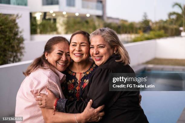 amigas latinas abrazándose y riendo en casa - mujeres mexicanas fotografías e imágenes de stock