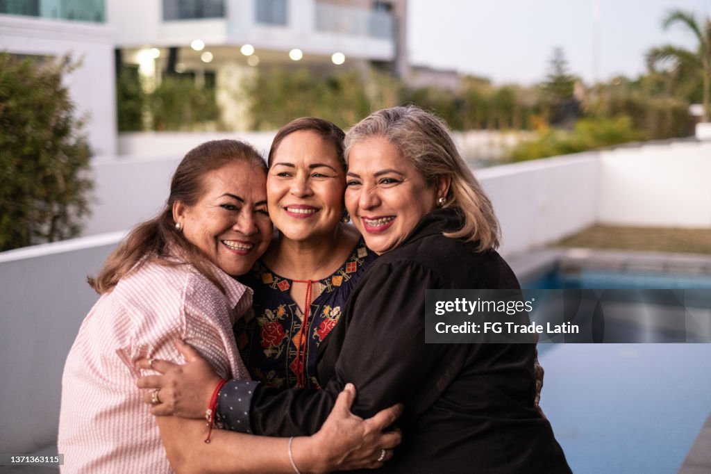 Female Latin friends hugging each other and laughing at home