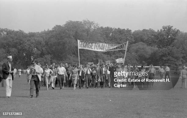Group of Civil Rights demonstrators, carrying a large Georgetown University banner, as they walk across the grass during the March on Washington for...