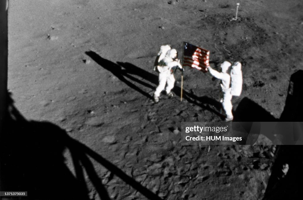 20 Jul 1969- Astronaut Neil A. Armstrong, stands on the left at the flag's staff. Astronaut Edwin E. Aldrin Jr., also pictured. Pic taken by the 16mm Data Acquisition Camera (DAC) mounted in the LM - deploy flag.
