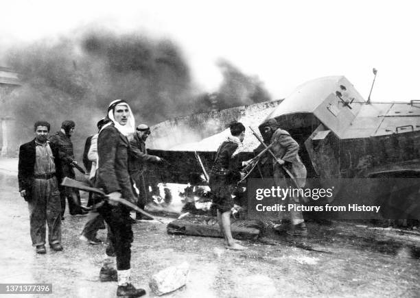 Palestinian fighters beside a burned-out Israeli Haganah supply truck near Jerusalem, Arab-Israeli War, 1948.