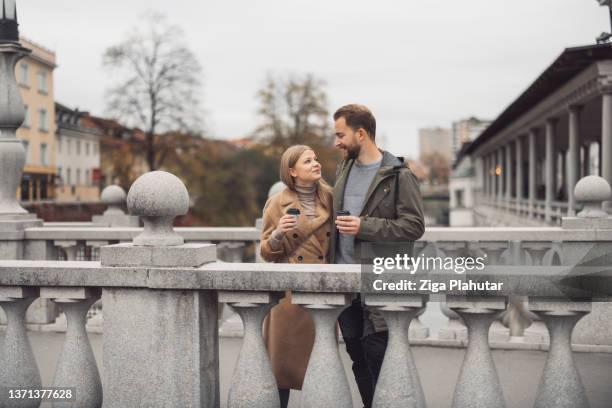 couple in love looking at each other, both holding coffee to go - spending stock pictures, royalty-free photos & images