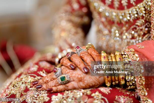 asian bride wearing jewelry in her arms and hands with henna tattoos. - indian bride closeup stock-fotos und bilder