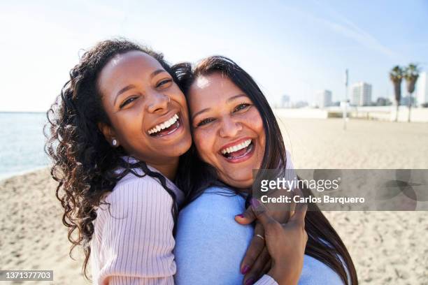 close up photo of mother and daughter smiling on the beach. - dochter stockfoto's en -beelden