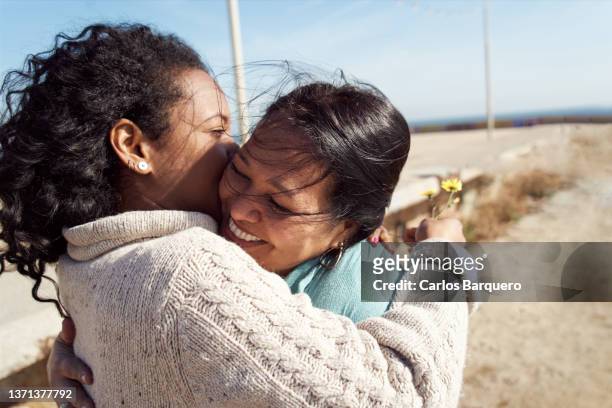 mother and daughter hugging outdoors. - mothers day beach fotografías e imágenes de stock