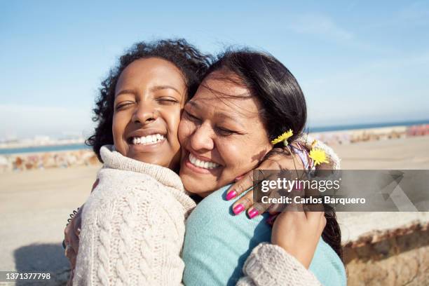 lovely photo of a mother and daughter hugging with a sea landscape. - mothers day beach fotografías e imágenes de stock