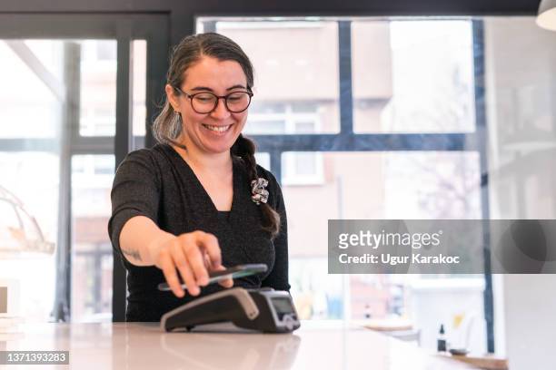 woman making contactless payment with smartphone at cafe - woman make up stock pictures, royalty-free photos & images