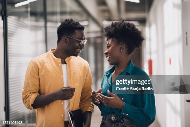 two black confident businesspersons talking and smiling in work space - black history stock pictures, royalty-free photos & images