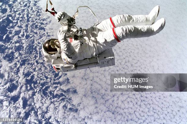 Backdropped against clouds 130 nautical miles below, astronaut Mark C. Lee floats freely without tethers as he tests the new Simplified Aid for EVA...