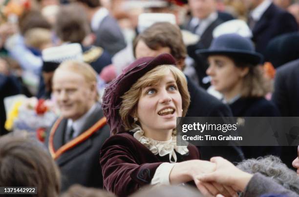 British Royal Diana, Princess of Wales , wearing a burgundy Jaeger outfit and a matching John Boyd hat with an ostrich feather, greeting well-wishers...