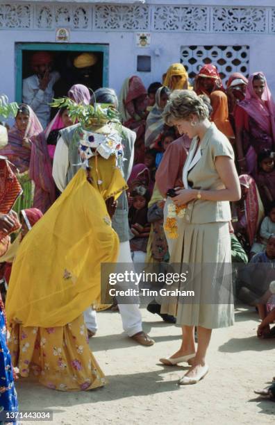 British Royal Diana, Princess of Wales , wearing a beige-and-white Catherine Walker dress with a pleated skirt, greets a local woman in a yellow sari...