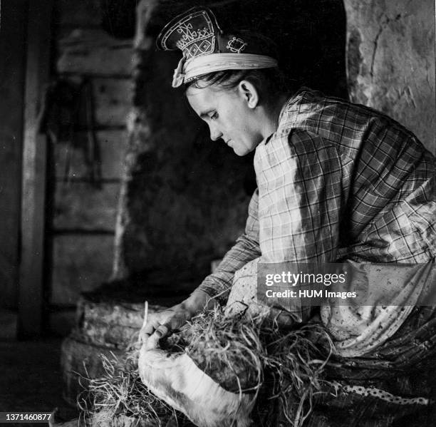 Finland History - ca. 1938 - Winter village. Every morning Skolt Sami wife is filling up her husband's 'nutukka' shoes with soft hay. Suenjel ,...