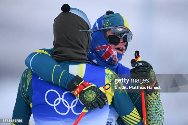 Phil Bellingham of Team Australia is embraced by teammate Seve de Campo after finishing during the Men's Cross-Country Skiing 50km Mass Start Free on...