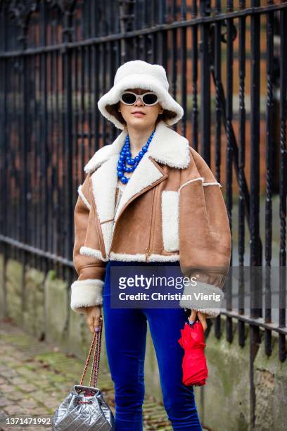 Guest is seen wearing bucket hat, brown shearling jacket, silver Chanel bag, blue velvet pants, necklace outside Bora Aksu during London Fashion Week...