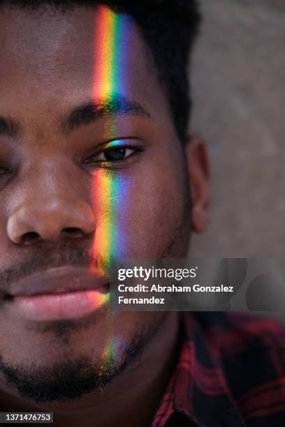 portrait of young man looking at camera with vertical light on his face with colors of rainbow - face projection stock pictures, royalty-free photos & images