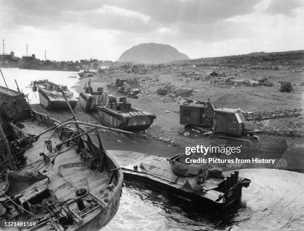 Destroyed American amtracs and other vehicles on a beach at Iwo Jima, Mount Suribachi in distance, March 1945.