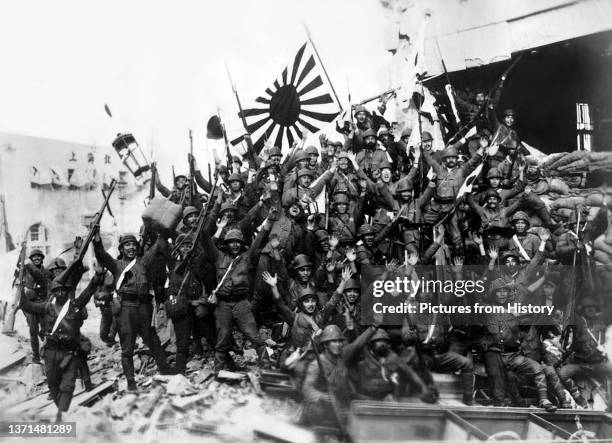 Soldiers of the Imperial Japanese army, waving the Japanese Naval Standard, celebrate victory at Shanghai, 1937.