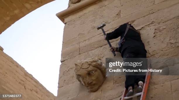 An ISIL militant uses a sledgehammer to destroy a colossal face on a wall in Hatra, a 3rd Century BCE Seleucid city 110km southwest of Mosul, March...