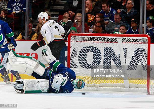Roberto Luongo of the Vancouver Canucks is on his side while Andrew Cogliano of the Anaheim Ducks skates behind the net after a goal during their NHL...