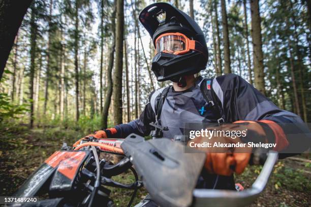 verticale mâle de pilote d’enduro de motocross à l’extérieur. concept sportif pour le sport automobile sur piste de sport. motard professionnel avec le casque et la moto de cascade. homme avec des vêtements de sport protecteurs. - motocross stock photos et images de collection