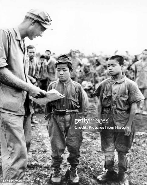 Marine talking with captured Japanese child soldiers. Battle of Okinawa, May 1945.