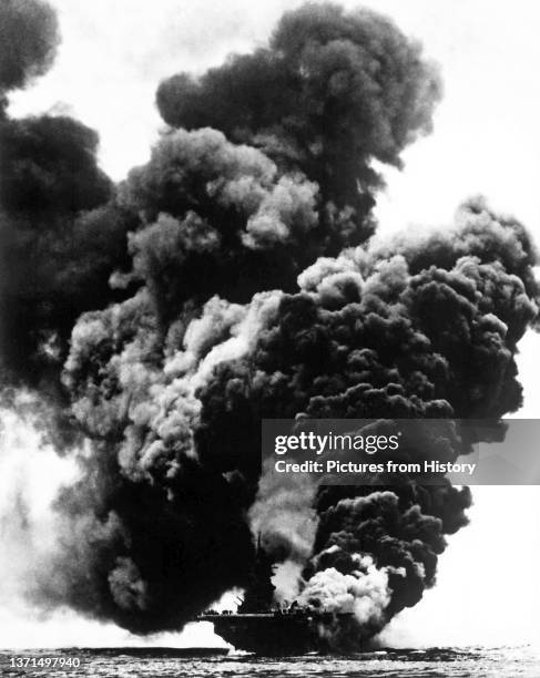 Aircraft carrier USS Bunker Hill ablaze after being hit by two kamikaze suicide planes. Photographed from USS Bataan on the morning of May 11 while...