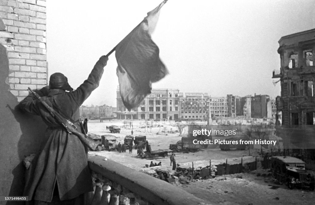 Russia/Germany: A victorious Red Army soldier raises the Soviet Flag over the ruins of Stalingrad, February 1943