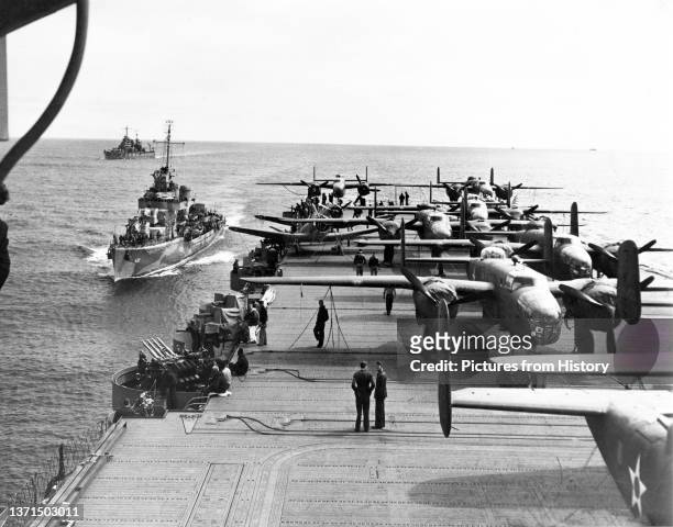 Some of the B-25 Mitchell Bombers of the Doolittle Raiders crowd the rear deck of the USS Hornet with two escort vessels following close in the...