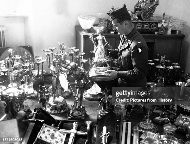 Soldier examines a solid gold statue, part of Hermann GoeringÕs private loot, found by the 7th U.S. Army in a mountainside cave near Schonau am...