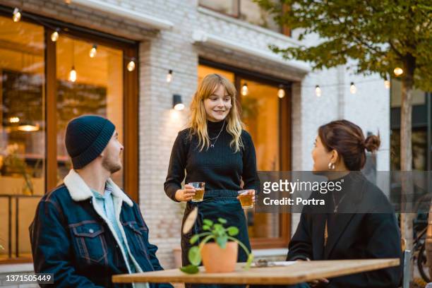 waitress serving tea to couple sitting at outdoor cafe table - waitress bildbanksfoton och bilder