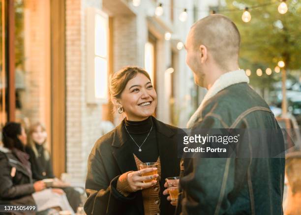 happy young couple talking outside cafe on a winter evening - berlin cafe stock pictures, royalty-free photos & images