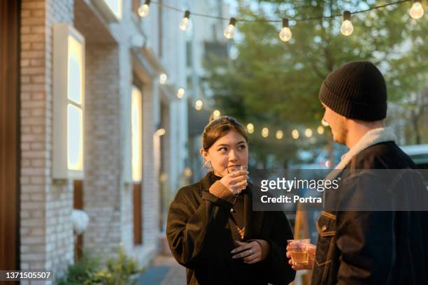 couple talking over a hot cup of tea on a winter evening outdoors - hot filipina women stock pictures, royalty-free photos & images