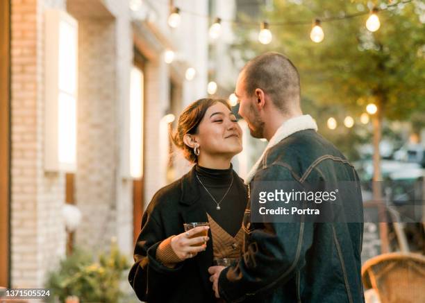 verliebtes paar kurz davor, sich vor einem café in der stadt zu küssen - dating stock-fotos und bilder