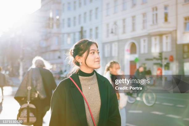 young asian woman walking down the street on a winter day - winter berlin bildbanksfoton och bilder