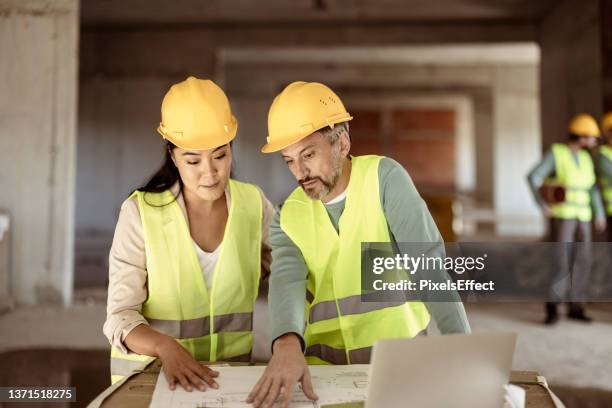 architects at construction site looking at blueprints - property developer stock pictures, royalty-free photos & images