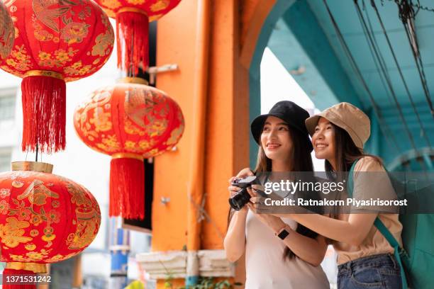 young asian women with her girlfriends lesbian lgbtq couple using camera to photograph while sightseeing and exploring china town in bangkok thailand - thailand city stock pictures, royalty-free photos & images