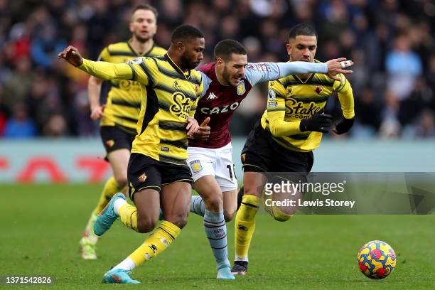 Emiliano Buendia of Aston Villa is challenged by Emmanuel Dennis and Imran Louza of Watford FC during the Premier League match between Aston Villa...