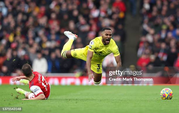 Rico Henry of Brentford is challenged by Cedric Soares of Arsenal during the Premier League match between Arsenal and Brentford at Emirates Stadium...