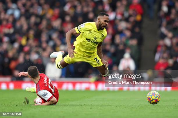 Rico Henry of Brentford is challenged by Cedric Soares of Arsenal during the Premier League match between Arsenal and Brentford at Emirates Stadium...