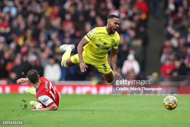 Rico Henry of Brentford is challenged by Cedric Soares of Arsenal during the Premier League match between Arsenal and Brentford at Emirates Stadium...