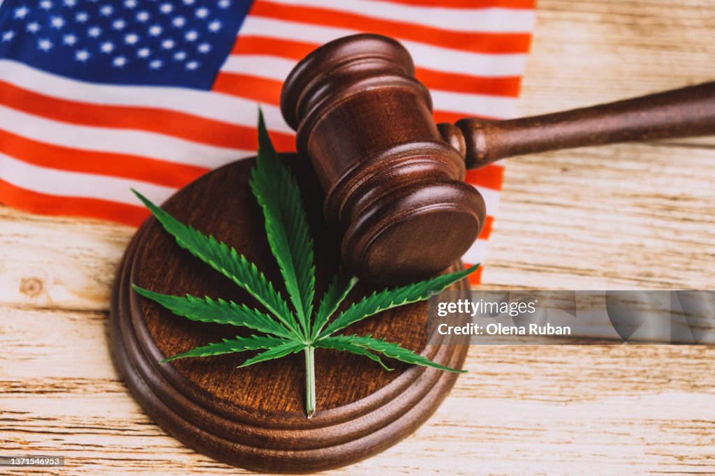 Cannabis leaf on sound block under gavel over US flag.
