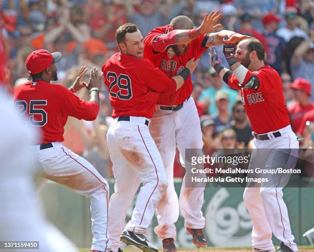 Jonny Gomes gets congratulated by Jackie Bradley, Jr., Daniel Nava, and Dustin Pedroia after scoring on Jonathan Herrera's walk off single to win the...
